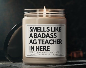 May include: A beige candle with a black label that reads "Smells like a badass AG teacher in here. Light this candle when you are feeling especially badass."