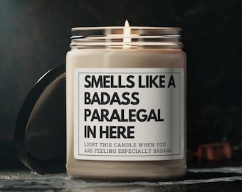 May include: A beige candle with a black label that reads "Smells like a badass paralegal in here. Light this candle when you are feeling especially badass."
