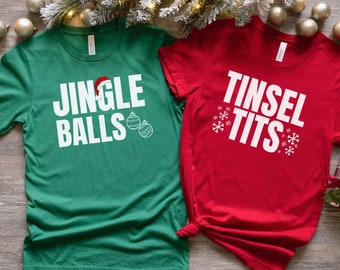 May include: Two green and red t-shirts with a Christmas theme. The green shirt says "Jingle Balls" with a Santa hat and baubles. The red shirt says "Tinsel Tits" with snowflakes.