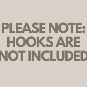 K&ouml;nnte beinhalten: Rechteckiges Bild mit dem Text "PLEASE NOTE: HOOKS ARE NOT INCLUDED" in dunkelgrauer Schrift. Der Text ist auf einem hellbeigen Hintergrund zentriert.