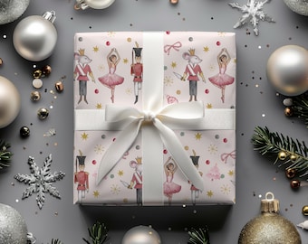 May include: A wrapped gift with a white ribbon, featuring a repeating pattern of illustrations. The pattern includes a mouse in a crown, a ballerina, and a toy soldier. The background is light pink with gold stars and red dots.