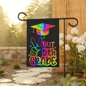 May include: A black garden flag with a rainbow tie-dye graduation cap and the text "Out 5th Grade" with a peace sign.