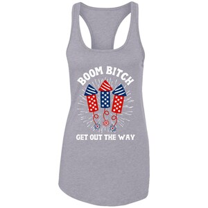 K&ouml;nnte beinhalten: Ein graues Tanktop mit dem Text "BOOM BITCH GET OUT THE WAY" in Wei&szlig;. Drei rot-wei&szlig;-blaue Feuerwerksk&ouml;rper befinden sich &uuml;ber dem Text.
