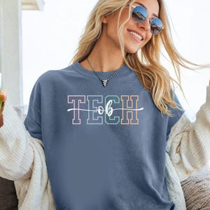 May include: A blue t-shirt with the text "TECH" in rainbow colors and a white cursive "ob" underneath.