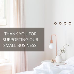 May include: A white bed with a white headboard and a white duvet cover. A small, white vase with a sprig of greenery sits on a bedside table with a rose gold lamp. The text "THANK YOU FOR SUPPORTING OUR SMALL BUSINESS!" is displayed on a grey background.