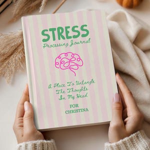 May include: A hardcover journal with a light pink and cream vertical striped cover. The text reads STRESS Processing Journal, A Place To Untangle The Thoughts In My Head, and FOR CHRISTINA. A pink line-art brain illustration is centered.