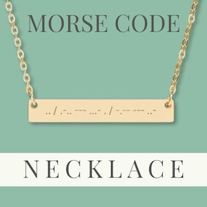 Peut inclure: Collier en code Morse doré avec un pendentif rectangulaire. Le pendentif affiche une série de points et de tirets, suspendus à une chaîne délicate. Les mots "MORSE CODE" et "NECKLACE" sont affichés au-dessus et en dessous du collier.