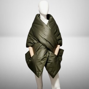 May include: A green quilted wrap with large pockets. The wrap is made of a soft, comfortable material and is designed to be worn as a scarf or a light jacket.