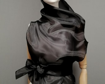 Blusa negra de cuello alto con cinturón, confeccionada en organza translúcida. Camisa transparente sin mangas. Blusa elegante y transparente para mujer. Prenda especial para cubrirse.