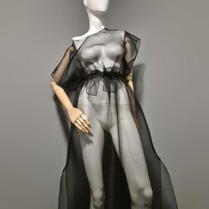 Vestido largo de organza negra transparente con superposición. Túnica sin mangas con cinturón, confeccionada en organza arrugada transparente.