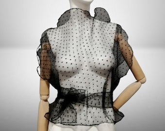 Blusa negra con cinturón y corte al bies, confeccionada en organza arrugada con pequeños lunares. Camisa transparente sin mangas. Elegante top para mujer. Una prenda de abrigo especial.