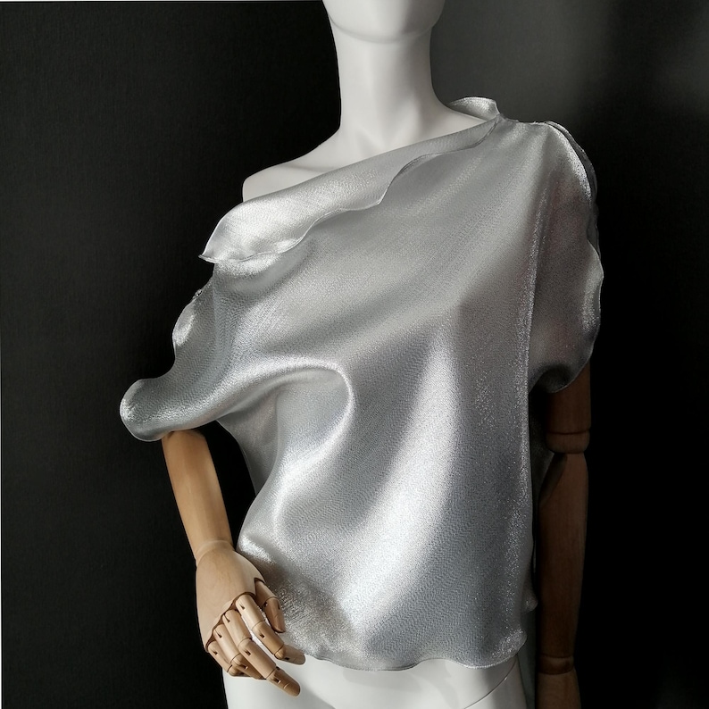 May include: A silver metallic off-the-shoulder top with a draped design.