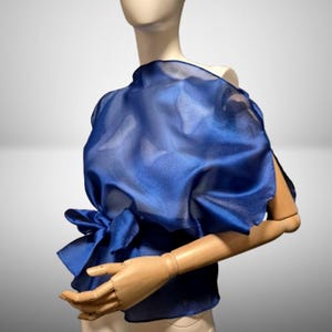 Blusa azul con cinturón y corte al bies, confeccionada en organza fluida y translúcida. Camisa transparente sin mangas. Top elegante y transparente para mujer. Prenda ideal para cubrirse.