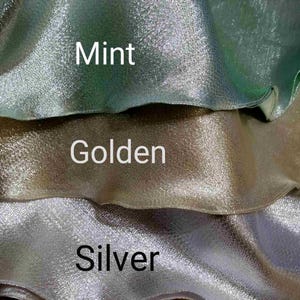 May include: Three swatches of fabric in different colors: mint, golden, and silver. The fabric has a shimmery, iridescent finish.