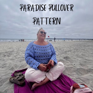 May include: A woman sits on a beach with a purple blanket, wearing a light blue crochet pullover and holding a red crochet project. The text "PARADISE PULLOVER PATTERN" is displayed at the top of the image.