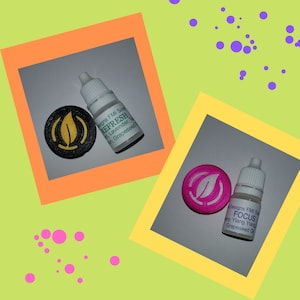 Op de afbeelding: Twee kleine flesjes etherische olie met etiketten waarop 'Refresh' en 'Focus' staat. De flesjes staan ​​naast kleine ronde schijven met een blaadjesontwerp. De 'Refresh'-schijf is zwart met een geel blad en de 'Focus'-schijf is roze met een wit blad.