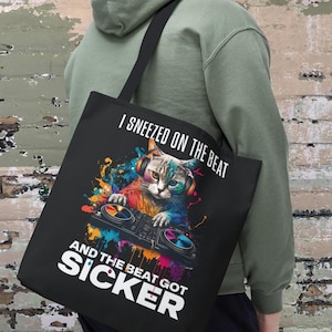 May include: Black tote bag with a colorful graphic of a cat wearing headphones and playing a DJ mixer. The text on the bag reads "I sneezed on the beat and the beat got sicker". The bag measures 16 inches by 16 inches.
