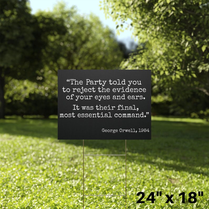 May include: A black sign with white text quoting George Orwell: "The Party told you to reject the evidence of your eyes and ears. It was their final, most essential command." The sign is 61cm x 46cm and is displayed on a metal stake in a grassy area.
