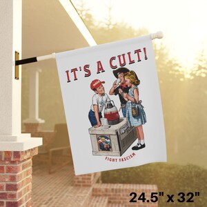K&ouml;nnte beinhalten: Eine wei&szlig;e Flagge mit dem Text "IT'S A CULT!" in roten Buchstaben. Die Flagge zeigt au&szlig;erdem eine Illustration von drei Kindern, die aus einem Krug trinken, der mit "Kool-Aid" beschriftet ist. Die Flagge hat den Text "FIGHT FASCISM" unten. Die Flagge ist 62,2 cm x 81,3 cm gro&szlig;.