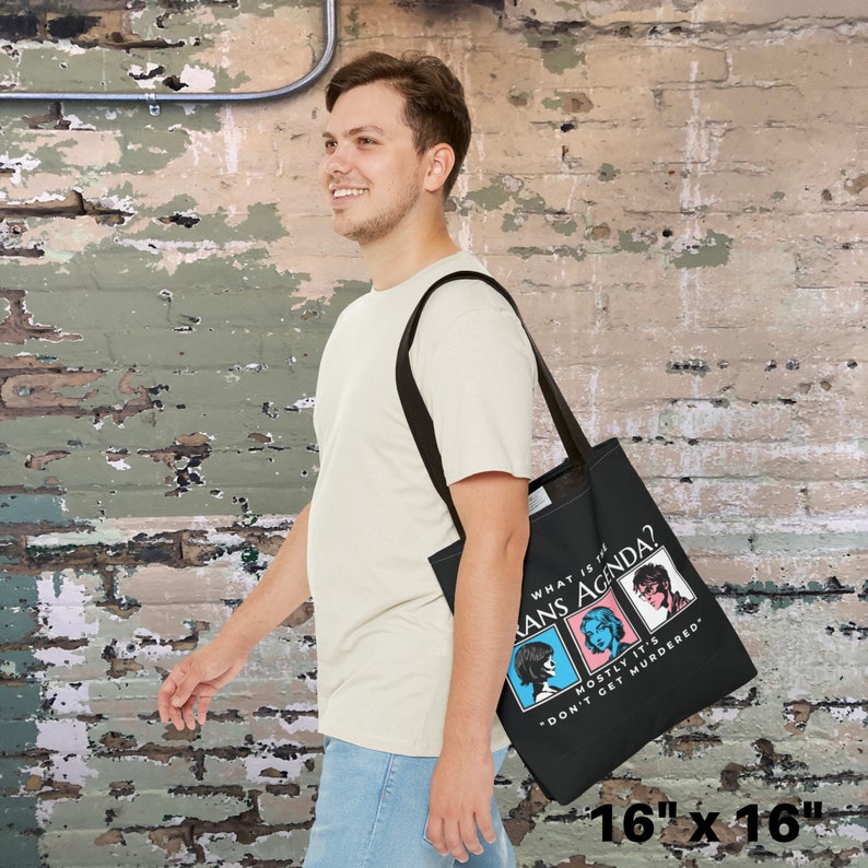 May include: Black tote bag with a white graphic that says "What is the Trans Agenda?" with three cartoon faces and the text "Mostly it's *Don't Get Murdered." The bag is 40.6 cm by 40.6 cm.