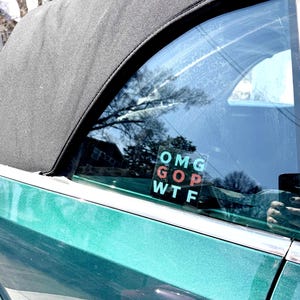 May include: A green convertible car with a sticker on the back window that says "OMG GOP WTF" in red, pink, and blue letters.
