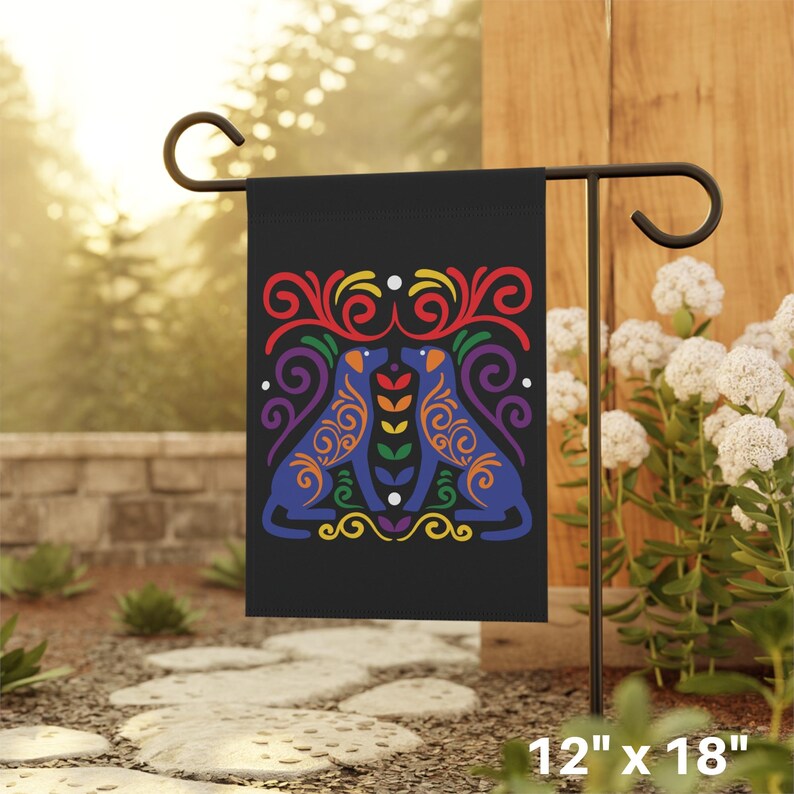 May include: A black garden flag with a rainbow-colored design of two dogs facing each other. The dogs are outlined in blue and have intricate patterns within their bodies. The flag is 12 inches by 18 inches.