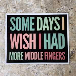 K&ouml;nnte beinhalten: Schwarzer Aufkleber mit dem Text "Some days I wish I had more middle fingers" in wei&szlig;er, gr&uuml;ner und rosa Schrift.