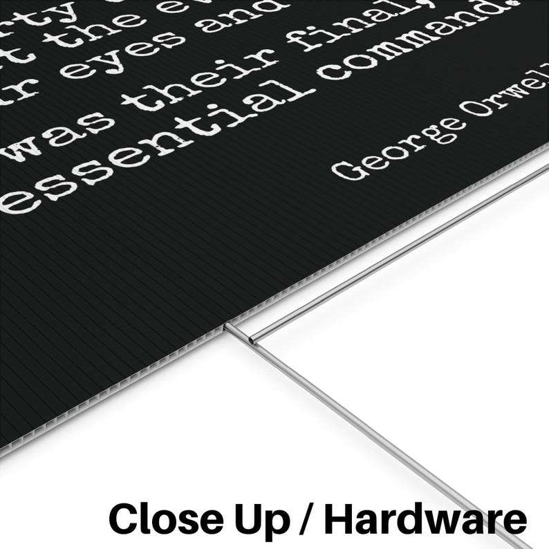 May include: Black sign with white text quoting George Orwell. The sign has a corrugated texture and is supported by a metal frame. The text reads "...was their final essential command."