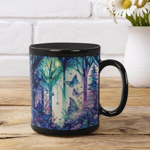 May include: Black ceramic mug with a colorful illustration of a forest scene with butterflies. The scene features trees, leaves, and a sunbeam.