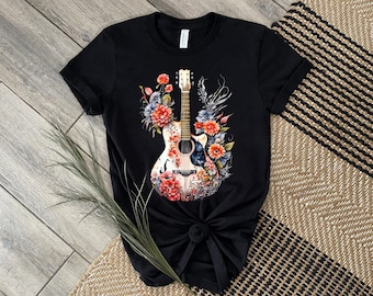 May include: Black t-shirt with a floral design featuring an acoustic guitar. The guitar is white with black accents and is surrounded by red, pink, and blue flowers.