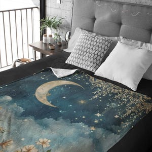 May include: A soft, blue and white throw blanket with a crescent moon and stars design. The blanket features a vintage, watercolor-like aesthetic with delicate floral details.
