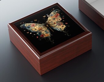 Puede incluir: Una caja de madera con una tapa negra que presenta una mariposa colorida hecha de flores y hojas. La mariposa tiene un cuerpo azul oscuro y alas con un patrón floral. La caja es de color marrón rojizo oscuro.