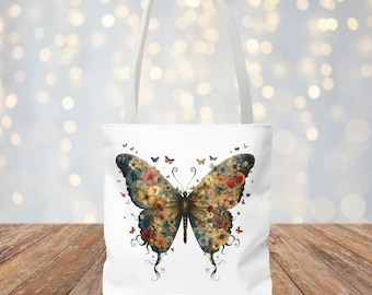 May include: White tote bag with a colorful butterfly design. The butterfly is made up of flowers and has a blue, green, and yellow color scheme.