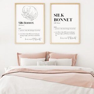 Puede incluir: Dos impresiones enmarcadas con ilustraciones en blanco y negro de un gorro de seda. El texto en las impresiones dice "Silk Bonnet" y define la palabra como un "promotor, ride-or-die, & guardi&aacute;n de tu cabello. Incluso cuando se desliza, desaparece milagrosamente por la noche, siempre te despertar&aacute;s a su lado. Cuidado del cabello del m&aacute;s alto nivel."