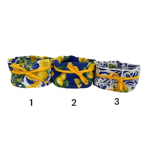 May include: Three fabric baskets with yellow ribbon ties. The baskets feature different patterns: lemons on blue, lemons on white, and a blue and white tile design. Each basket is numbered 1, 2, and 3.