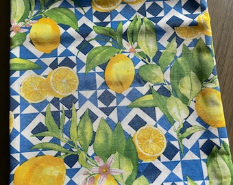 May include: A white tablecloth with a blue and white geometric pattern and a lemon print. The tablecloth features yellow lemons, green leaves, and pink flowers.