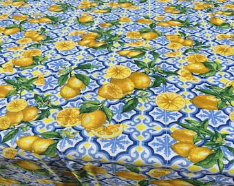 May include: A white tablecloth with a blue and yellow lemon pattern. The tablecloth features a repeating pattern of lemons, lemon slices, and green leaves on a blue and white tiled background.