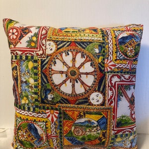 May include: A decorative pillow with a colorful patchwork design featuring a repeating pattern of wheels, lemons, and other geometric shapes. The pillow is made of a soft, textured fabric.