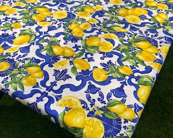May include: A white tablecloth with a blue and yellow lemon pattern. The tablecloth has a blue and white geometric pattern with lemons and leaves.
