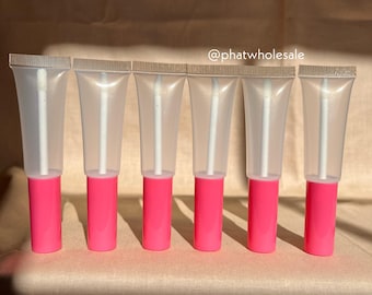 Puede incluir: Seis tubos de plástico transparente con tapas rosas y aplicadores blancos. Los tubos están vacíos y listos para llenarse con brillo de labios u otros líquidos.  @phatwholesale