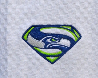 Puede incluir: Toalla de cocina blanca con un logotipo bordado de los Seattle Seahawks en verde, azul y plateado, en forma de símbolo de Superman.