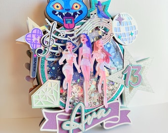 May include: A layered birthday cake topper featuring three stylized figures, musical notes, a disco ball, and a blue cat face. The topper includes the name "Ava" and the number "13" in a purple and teal color scheme.