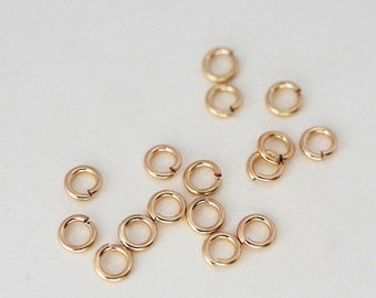 May include: A collection of gold jump rings, a type of jewelry finding used for connecting chains, cords, and other jewelry components.
