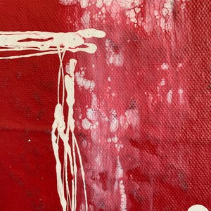 Puede incluir: Pintura abstracta con salpicaduras y goteos de pintura blanca sobre un fondo rojo. La pintura blanca crea un efecto texturizado.