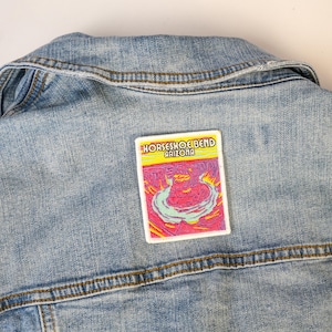 May include: A blue denim jacket with a white patch that says "Horseshoe Bend Arizona" and features a colorful illustration of the Horseshoe Bend.
