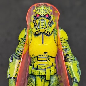 Bossk (yellow) by Tiddy Bean Toys. Hand molded and cast. 2 points of articulation. Glows in the dark! UV Reactive. Includes PVC cape