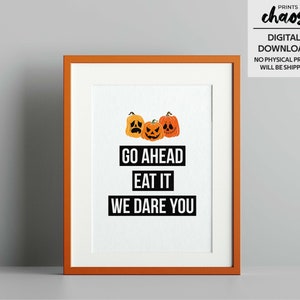 Puede incluir: Una descarga digital imprimible con tres calabazas naranja en forma de jack-o'-lantern con diferentes expresiones faciales. El texto "GO AHEAD EAT IT WE DARE YOU" está impreso debajo de las calabazas.