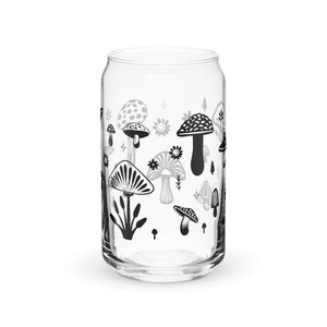 May include: A clear glass can with a black and white mushroom design. The mushrooms are stylized and have different shapes and sizes. The can is perfect for serving beverages.
