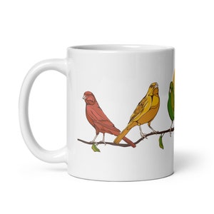 May include: White ceramic mug with a colorful illustration of four birds perched on a branch. The birds are red, yellow, and green.