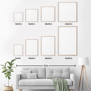 May include: A white wall with eight different sized picture frames, ranging from 11x14 inches to 24x36 inches. The frames are arranged in two rows, with the larger frames at the bottom. A gray couch with a green throw blanket is in front of the wall. A potted plant and a floor lamp are on either side of the couch.